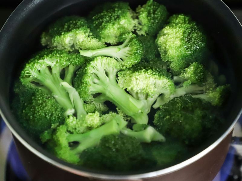bright green broccoli florets boiling in a pot for a fresh, healthy me image
