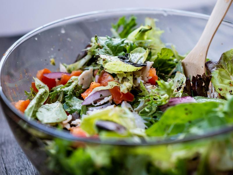 close-up of a vibrant fresh salad in a glass bowl with a wooden spatul image