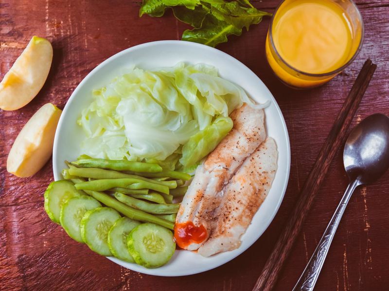 colorful dish featuring steamed fish, veggies, cucumber, and a glass o image