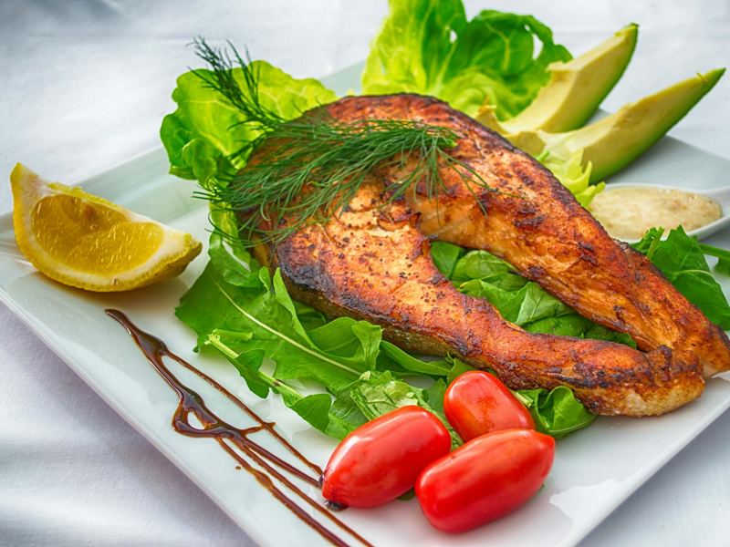 delicious grilled salmon served with fresh vegetables and herbs on a w image