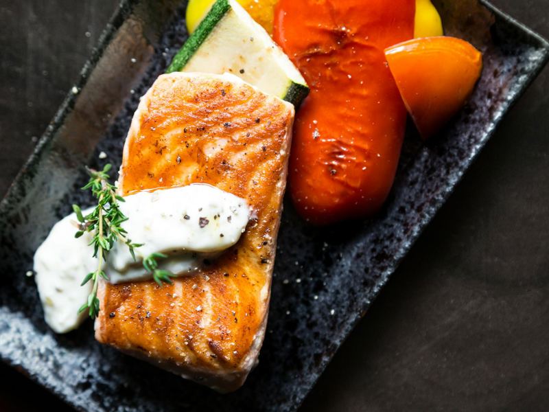 delicious grilled salmon served with roasted vegetables and herb sauce image
