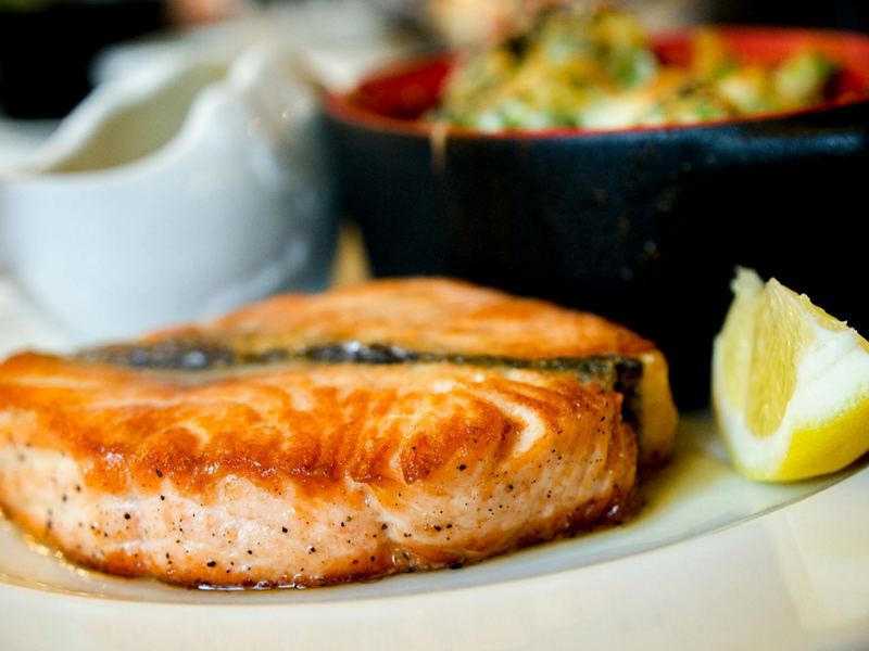 delicious pan-seared salmon steak garnished with a lemon slice, showca image
